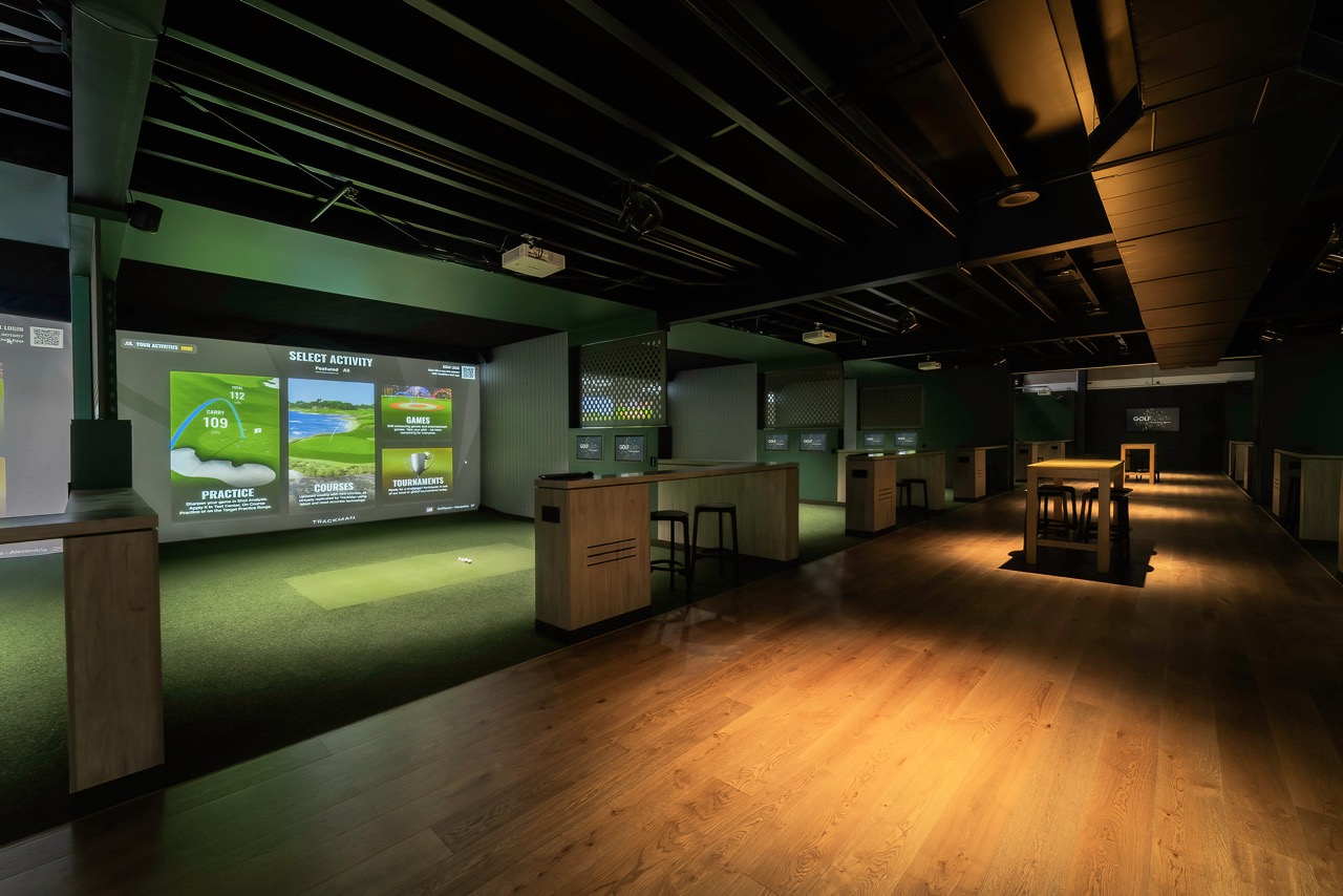 TrackMan simulator bays lit for an evening event at GolfSpace